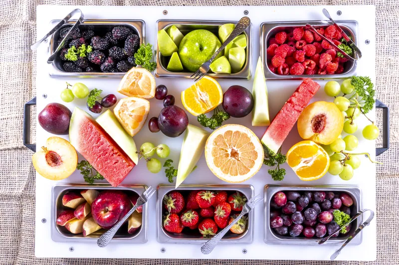 Fruit buffet in stainless pans on a DisplayPrep board