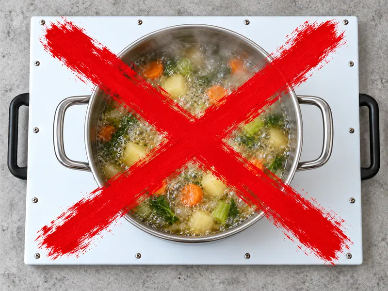 A pot of boiling vegetables standing on a DisplayPrep board, crossed out with a large red X: never put hot pots on the board